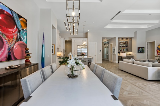 dining room featuring a notable chandelier, light parquet floors, and indoor bar