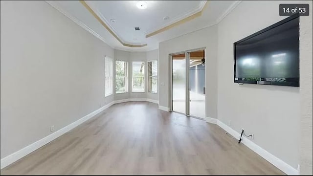 empty room featuring ornamental molding, light hardwood / wood-style floors, and a tray ceiling