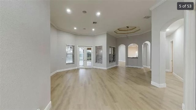 unfurnished living room with ornamental molding, a towering ceiling, and light hardwood / wood-style flooring