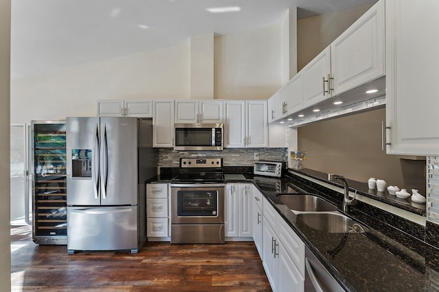 kitchen featuring dark wood-type flooring, sink, appliances with stainless steel finishes, dark stone counters, and white cabinets