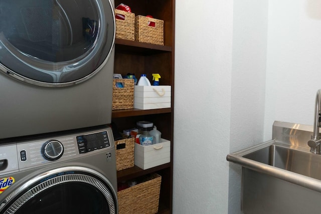 clothes washing area featuring stacked washing maching and dryer and sink