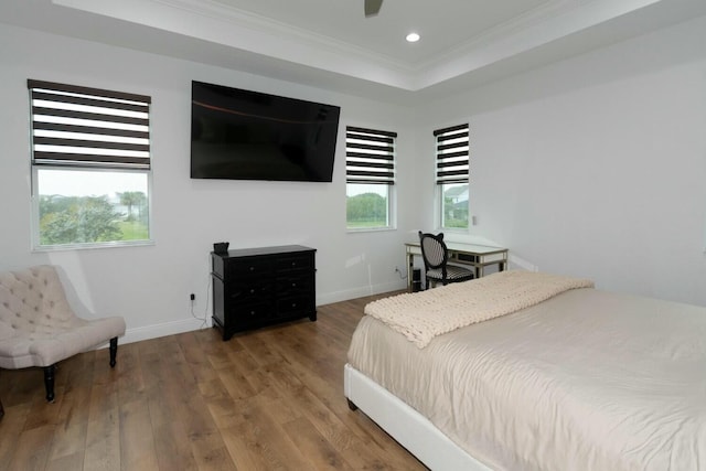 bedroom with a raised ceiling, ornamental molding, hardwood / wood-style flooring, and ceiling fan