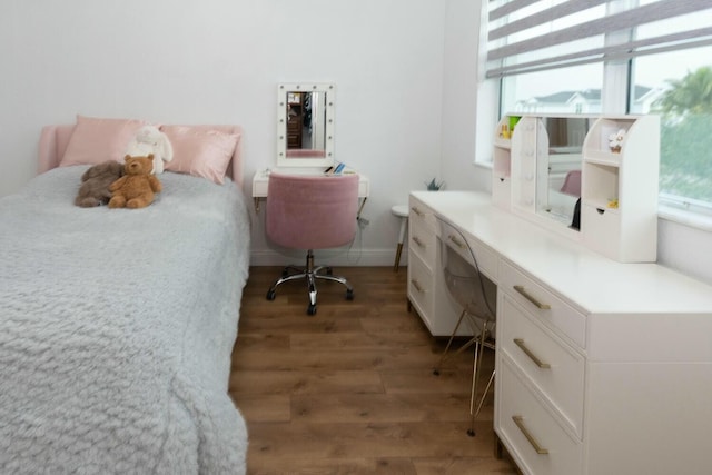 bedroom featuring built in desk and hardwood / wood-style floors