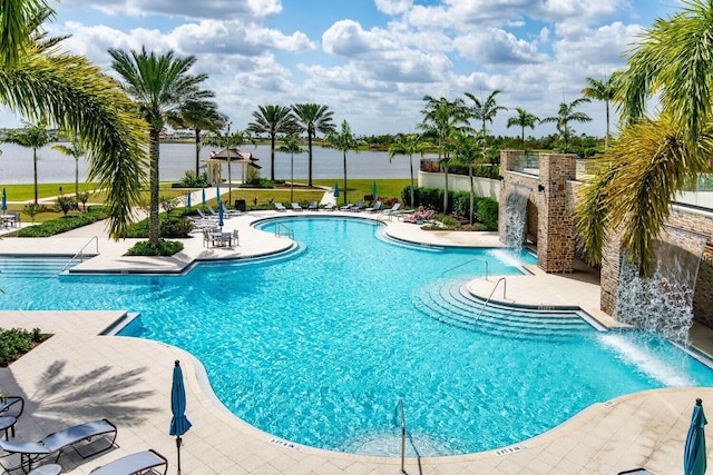 view of pool featuring pool water feature, a water view, and a patio