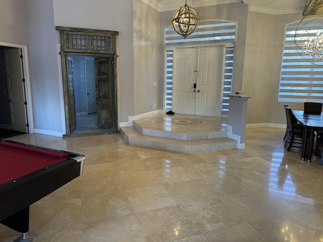 entryway with an inviting chandelier, billiards, crown molding, and a high ceiling