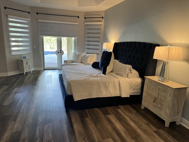 bedroom with a barn door, access to exterior, dark hardwood / wood-style flooring, and french doors