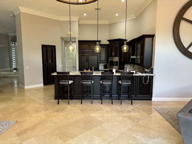 kitchen featuring a kitchen bar, paneled built in refrigerator, ornamental molding, light stone countertops, and a kitchen island with sink