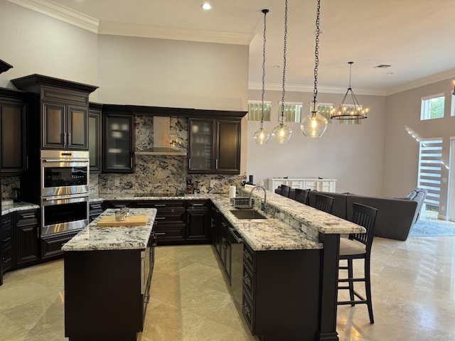 kitchen with sink, a breakfast bar area, kitchen peninsula, stainless steel double oven, and wall chimney range hood