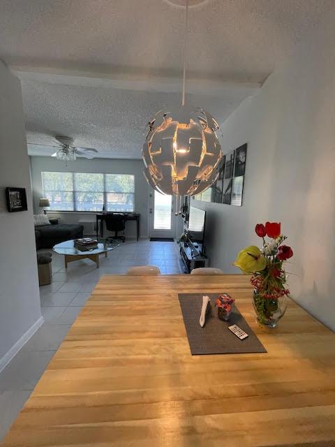 tiled dining space with ceiling fan and a textured ceiling