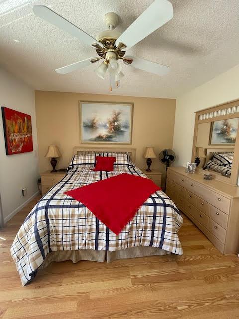 bedroom with ceiling fan, a textured ceiling, and light wood-type flooring