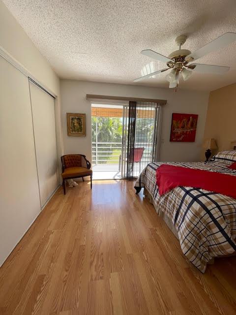 bedroom with access to exterior, light hardwood / wood-style flooring, a closet, and a textured ceiling