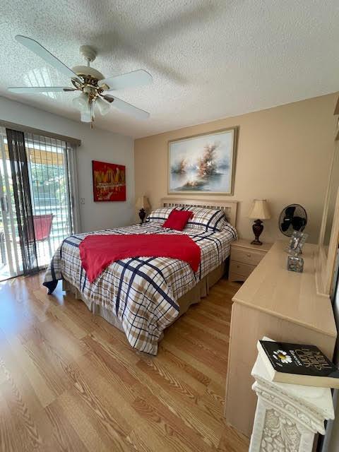 bedroom with ceiling fan, a textured ceiling, access to exterior, and light hardwood / wood-style floors