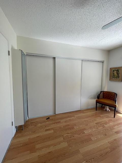 interior space featuring ceiling fan, hardwood / wood-style floors, a textured ceiling, and a closet