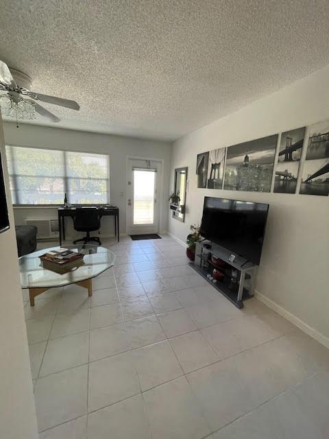 tiled living room featuring ceiling fan and a textured ceiling