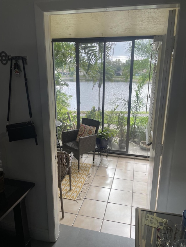 doorway with light tile patterned flooring and a water view