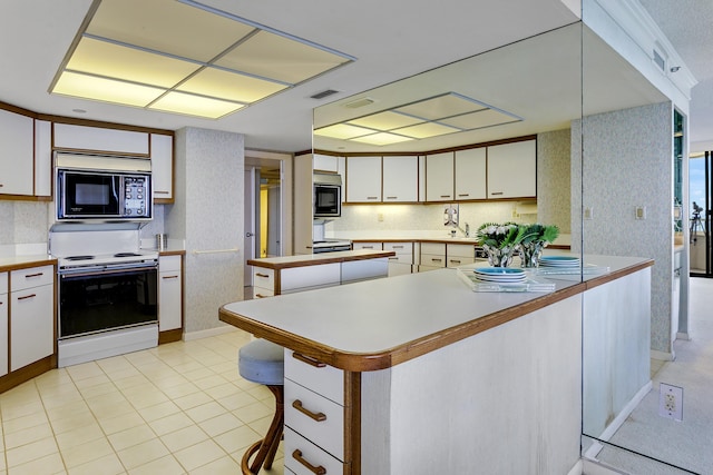 kitchen with black microwave, white electric range, and white cabinets