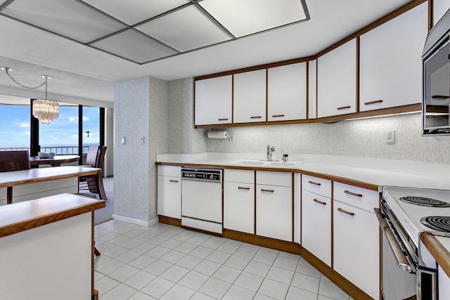 kitchen with white cabinetry, sink, pendant lighting, and white appliances