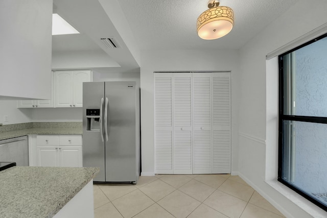 kitchen featuring white cabinetry, stainless steel appliances, light tile patterned flooring, and a textured ceiling