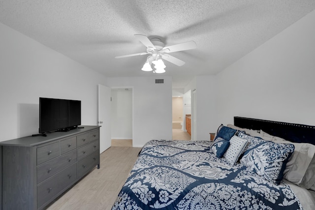 bedroom featuring ceiling fan, light hardwood / wood-style flooring, and a textured ceiling