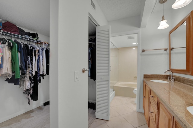 full bathroom featuring tile patterned flooring, vanity, toilet, bathing tub / shower combination, and a textured ceiling