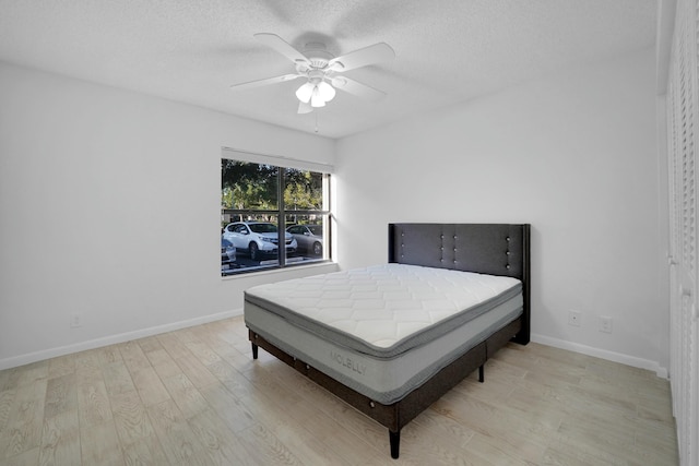 bedroom with ceiling fan, light hardwood / wood-style floors, and a textured ceiling