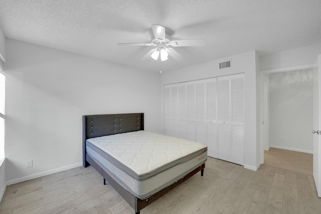 bedroom with ceiling fan, light hardwood / wood-style floors, a closet, and a textured ceiling