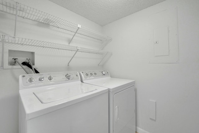 laundry room featuring a textured ceiling, washer and clothes dryer, and electric panel