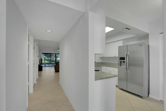 hallway featuring light tile patterned flooring and a textured ceiling