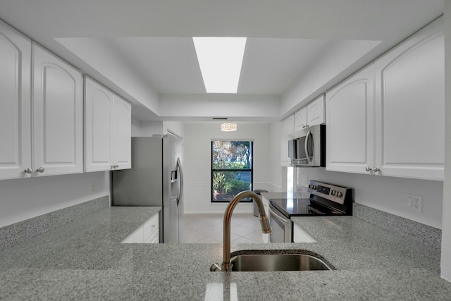 kitchen with white cabinetry, sink, a skylight, and stainless steel appliances