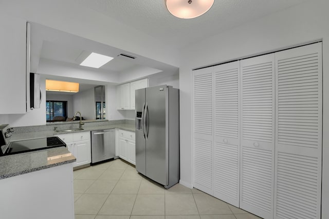 kitchen with sink, light tile patterned floors, white cabinetry, stainless steel appliances, and light stone counters