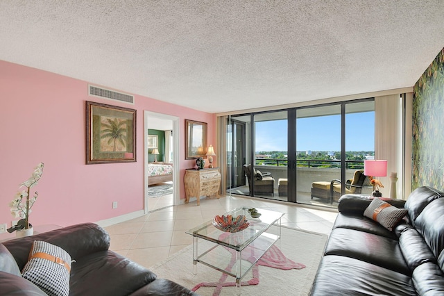 living area featuring a textured ceiling, light tile patterned flooring, visible vents, baseboards, and floor to ceiling windows