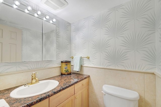 half bath featuring visible vents, vanity, toilet, and wallpapered walls