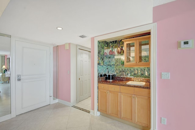 bar featuring indoor wet bar, light tile patterned floors, visible vents, a sink, and baseboards