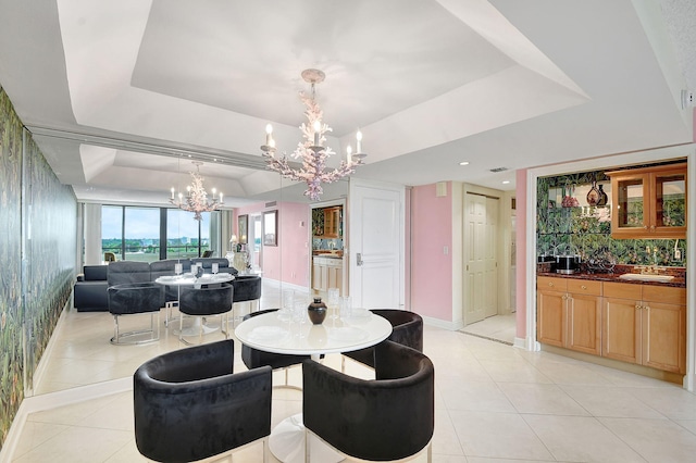 dining area featuring light tile patterned floors, a notable chandelier, baseboards, wet bar, and a tray ceiling