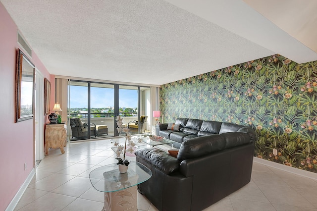 living room with light tile patterned floors, a textured ceiling, baseboards, and wallpapered walls