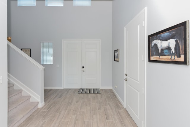 foyer entrance with a high ceiling and light hardwood / wood-style flooring