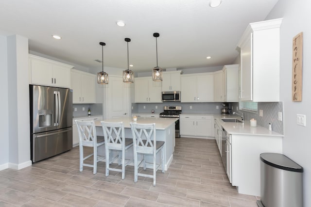 kitchen with sink, stainless steel appliances, a kitchen breakfast bar, a kitchen island, and decorative light fixtures