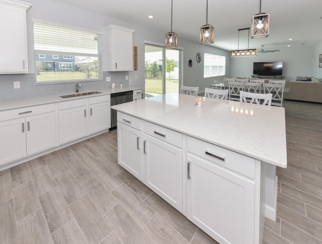 kitchen featuring sink, a center island, dishwasher, decorative backsplash, and white cabinets