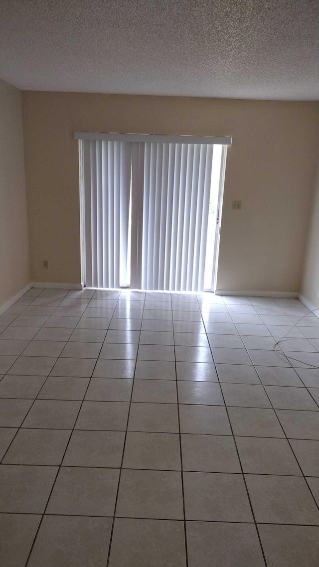 tiled spare room featuring a textured ceiling