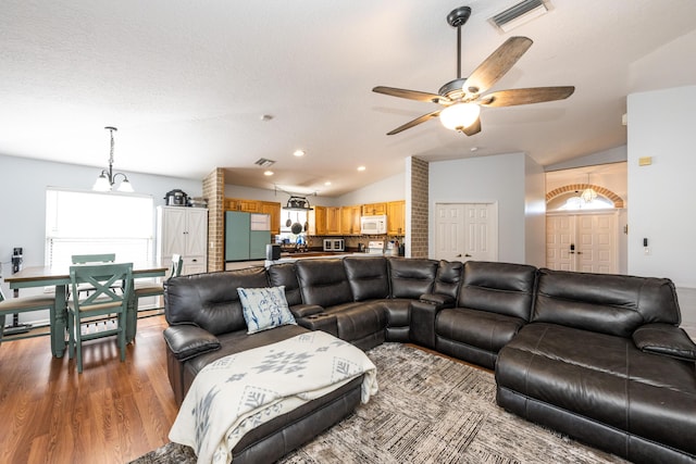 living room featuring wood-type flooring, lofted ceiling, ceiling fan, and a textured ceiling