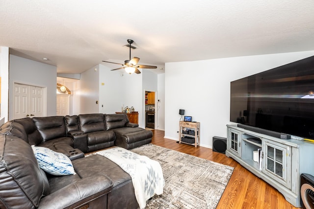 living room with lofted ceiling, hardwood / wood-style flooring, a textured ceiling, and ceiling fan