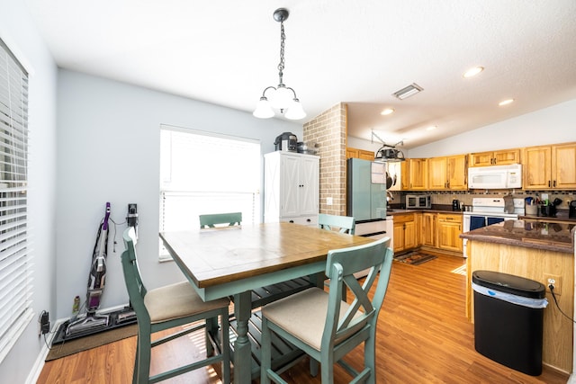 dining space with vaulted ceiling and light wood-type flooring