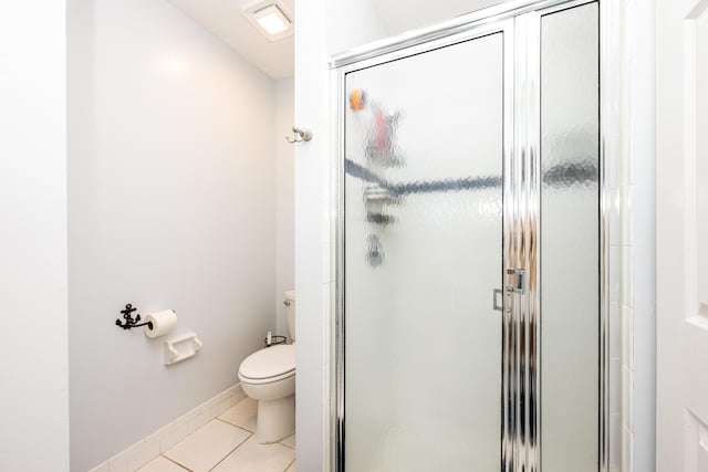 bathroom with tile patterned floors, toilet, and a shower with door