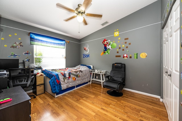 bedroom featuring lofted ceiling, a closet, ceiling fan, and light wood-type flooring