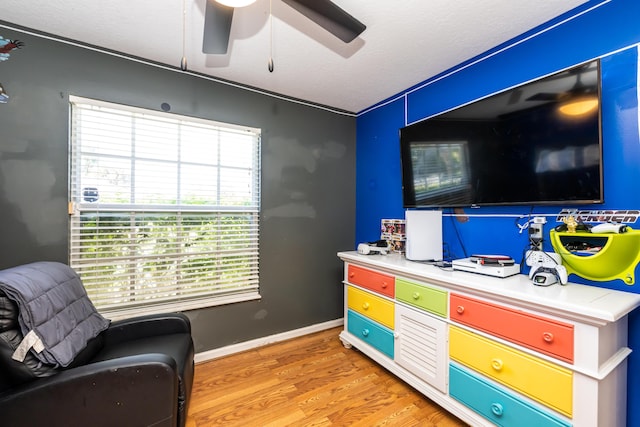 playroom with ceiling fan, light hardwood / wood-style floors, and a textured ceiling