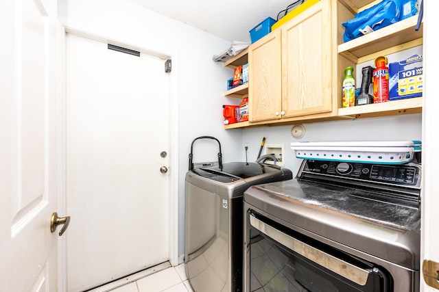 laundry area with light tile patterned floors, washing machine and dryer, and cabinets