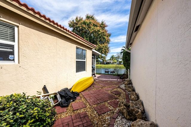 view of side of property featuring a patio and a water view