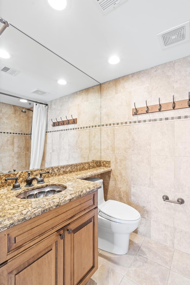 bathroom with tile walls, vanity, tile patterned floors, and toilet