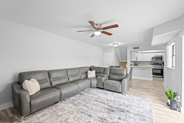 living room with ceiling fan and light hardwood / wood-style flooring