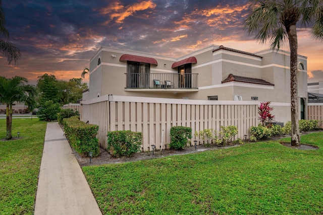 view of front of home with a yard and a balcony